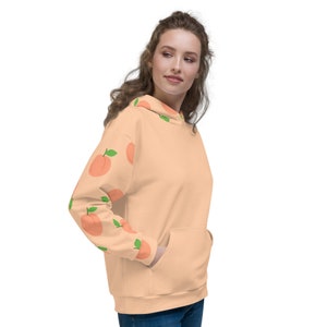 May include: A peach-colored hoodie with a peach pattern on the sleeves. The hoodie has a drawstring hood and a kangaroo pocket.