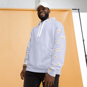 May include: A light blue hoodie with a white drawstring and white daisy print on the sleeves. The model is wearing a white baseball cap.