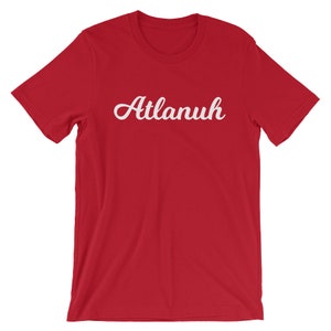 May include: Red short-sleeved t-shirt with the word "Atlanuh" printed in white cursive lettering.