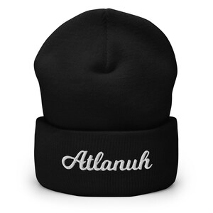 May include: Black beanie with a white embroidered cursive word "Atlanuh" on the cuff.