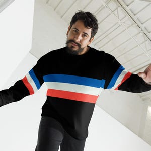 May include: A black long-sleeved shirt with red, white, and blue horizontal stripes. The shirt has a crew neck.