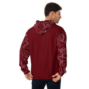 May include: Burgundy hoodie with white floral pattern on the sleeves. The hoodie has a drawstring hood and a kangaroo pocket.