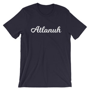 May include: A navy blue t-shirt with the word "Atlanuh" printed in white cursive lettering.