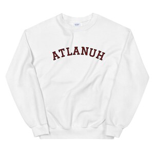 May include: White sweatshirt with a red "ATLANUH" text printed on the front in a collegiate-style font.