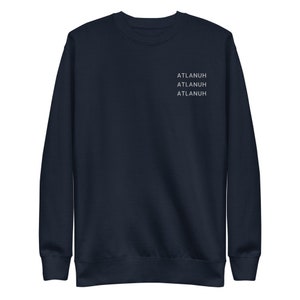 May include: Navy blue sweatshirt with the word "ATLANUH" printed three times in white on the upper chest. The sweatshirt has a crew neck and long sleeves. A casual, comfortable garment.