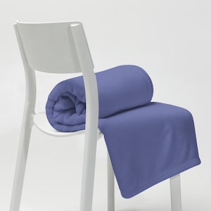 May include: A soft, blue fleece throw blanket folded over a white chair. The blanket is a solid color with no patterns.