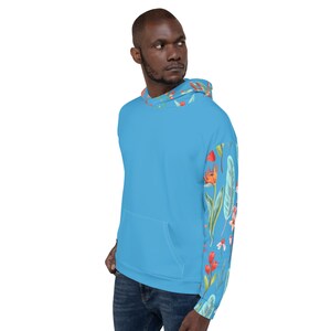 May include: A light blue hoodie with a floral print on the sleeves. The print features red, orange, and green flowers and leaves.