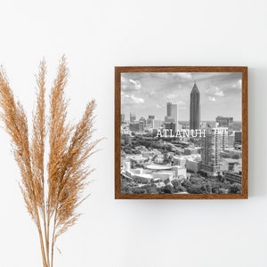 May include: Black and white photograph of the Atlanta skyline with the text "ATLANTA" printed in white on the image. The photograph is framed in a brown wood frame.