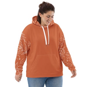 May include: A rust-colored hoodie with white leaf designs on the sleeves. The hoodie has a drawstring hood and a kangaroo pocket.
