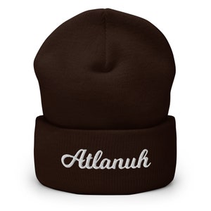 May include: A brown knit beanie with a white embroidered name "Atlanuh" on the front.
