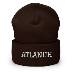May include: A brown knit beanie with a white embroidered logo that says "ATLANUH".