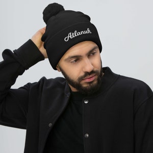 May include: Black beanie with a pom pom on top and the word "Atlanuh" embroidered in white on the front.