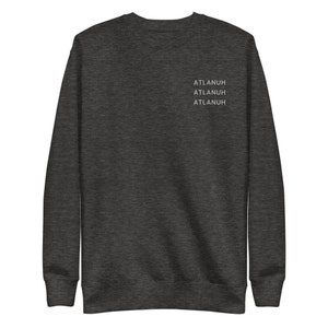 May include: Dark gray sweatshirt with the word "ATLANUH" printed three times in white on the upper chest area. The sweatshirt has a crew neck and long sleeves. The fabric appears soft and comfortable.