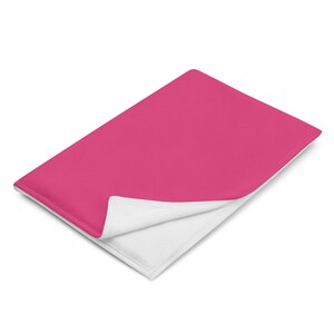 May include: A pink fleece blanket with a white underside. The blanket is folded in half and the pink side is facing up.