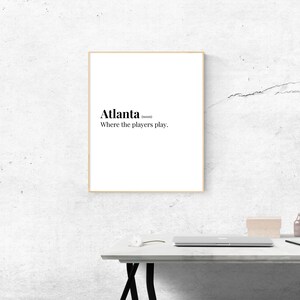 May include: A framed print with the text "Atlanta (noun) Where the players play."
