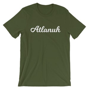 May include: A green short-sleeved t-shirt with the word "Atlanuh" printed in white cursive lettering.