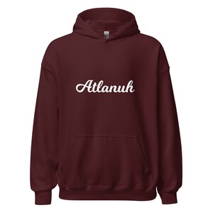 May include: A maroon hoodie with a white cursive inscription that reads "Atlanuh".