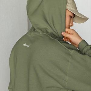 May include: A green hooded sweatshirt with the word "Altanuh" embroidered on the back.