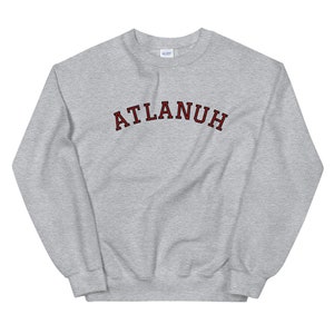 May include: A gray sweatshirt with the word "ATLANUH" printed in red with a black outline.