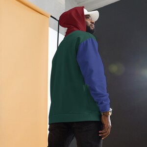 May include: A green, blue, and red color block hoodie with a hood. The hoodie has a white hat on top.