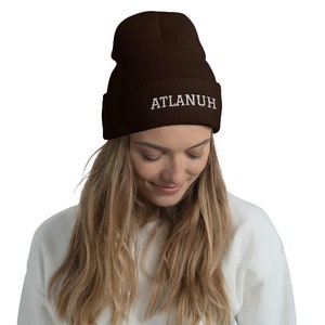 May include: A brown beanie with the word "ATLANUH" embroidered in white on the front.