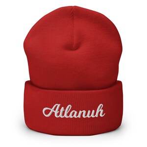 May include: Red knit beanie with a white embroidered name "Atlanuh" on the cuff.