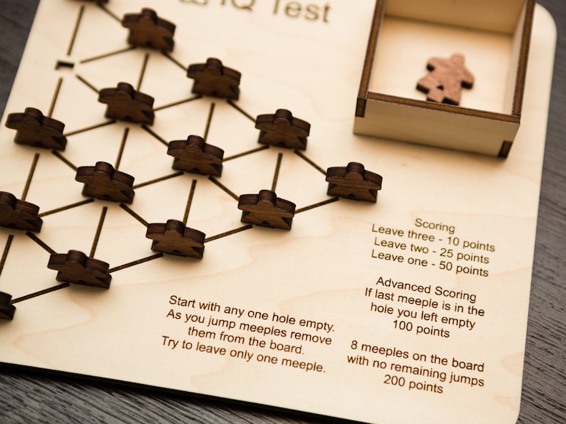 May include: Wooden IQ test game with a light wood board and dark wooden meeples. The game board has a network of lines and holes, with instructions and scoring details printed on the board. A small wooden box holds extra meeples.