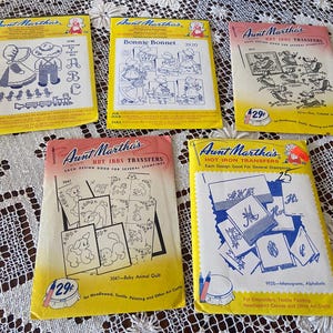 May include: Five vintage Aunt Martha's hot iron transfer packets featuring various designs including a Bonnie Bonnet, baby animals, monograms, and alphabets. Each paper envelope displays black line art illustrations on yellow or pink backgrounds.