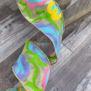 May include: A yellow, pink, blue, and green floral ribbon with a sheer, embroidered design.