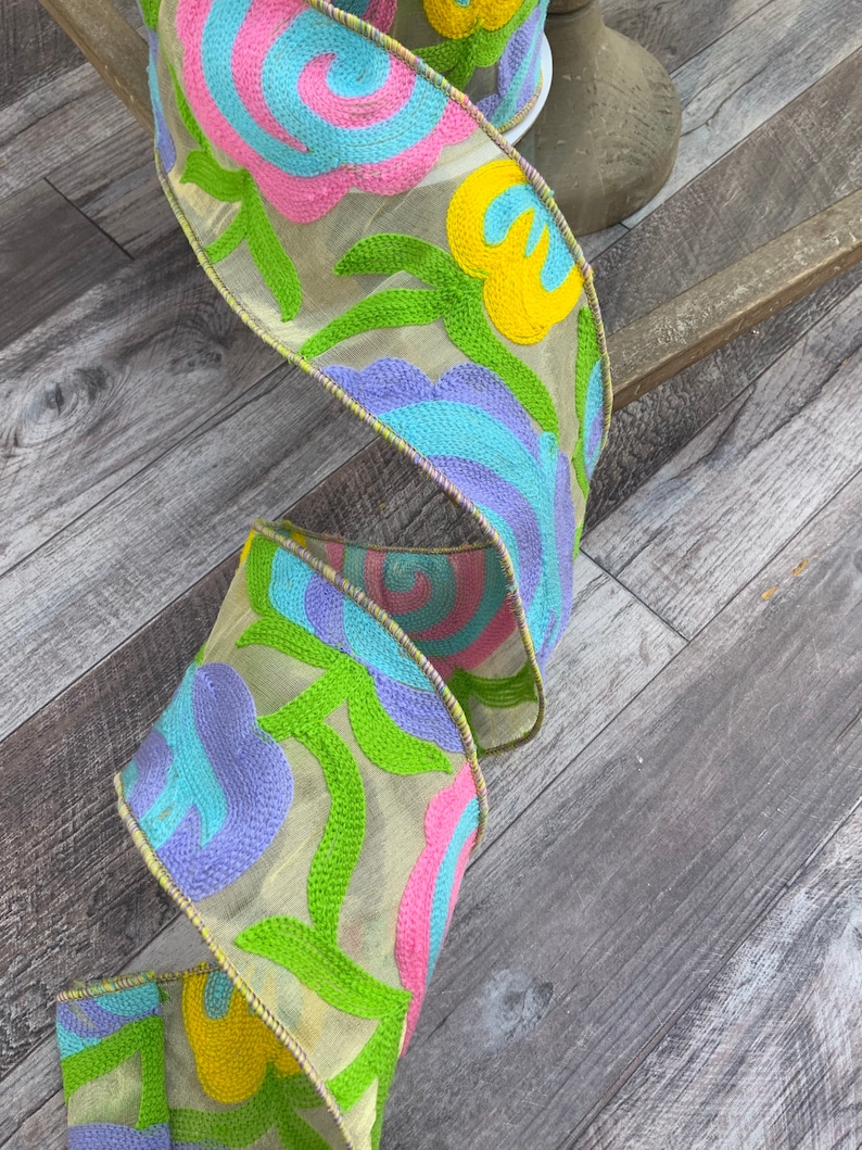 May include: A yellow, pink, blue, and green floral ribbon with a sheer, embroidered design.