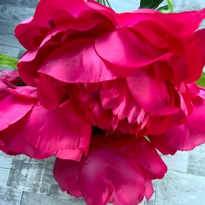 May include: A bouquet of bright pink artificial peonies with green leaves.