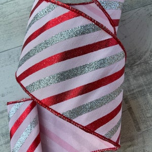 May include: Pink and red striped ribbon with silver glitter. The ribbon has a wired edge and is perfect for crafting.