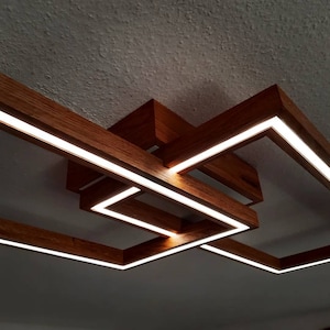 Könnte beinhalten: Eine moderne Deckenleuchte aus Holz mit integrierten LED-Leuchten. Die Leuchte besteht aus mehreren rechteckigen Rahmen, die ein geometrisches Muster bilden.