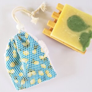 May include: A blue and yellow mesh bag with a white drawstring closure. The bag is filled with a bar of soap with green and yellow swirls.