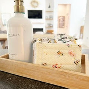 May include: A wooden tray with a white ceramic soap dispenser with a gold pump and a patterned soap bar.