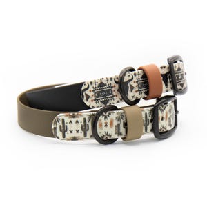 May include: Two dog collars with black hardware and matte keepers. The top collar is cream with a black bull skull pattern. The bottom collar is cream with a cactus and desert plant pattern. Both collars have solid-colored inner bands in black and olive.