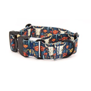Puede incluir: Un collar para perros con un patr&oacute;n azul oscuro de calaveras de toro blancas y flores naranjas. El collar tiene una hebilla de metal negro y una anilla en D de metal negro para sujetar la correa.