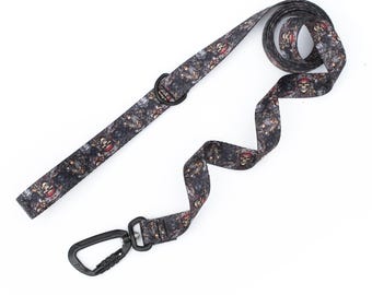 May include: A dog leash with a black and gray pirate skull pattern. The leash has a black metal clip and a black metal ring. The leash is made of a durable material and is designed for pet owners.