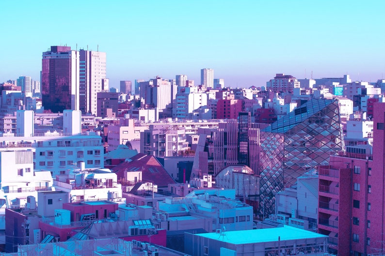 Puede incluir: Una vista a&eacute;rea de un horizonte urbano con una mezcla de edificios modernos y tradicionales. Los edificios son principalmente blancos y grises, con algunos acentos rosados y azules. El cielo es de un azul claro.