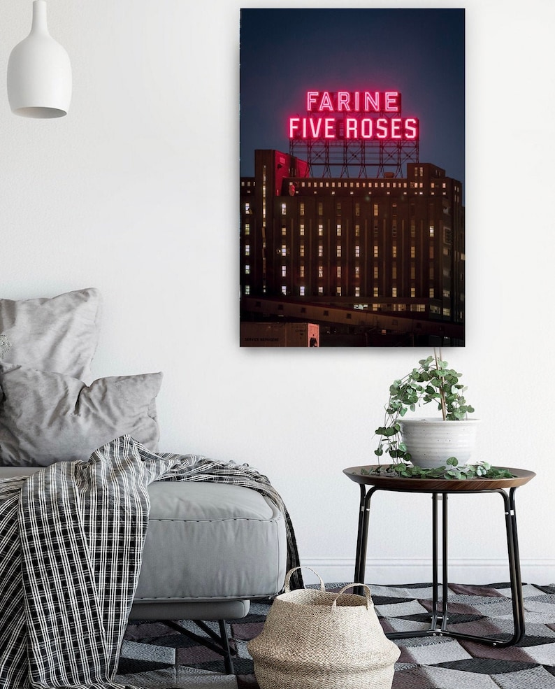 May include: A night-time view of a large building with a neon sign that reads "Farine Five Roses". The building is lit up with windows and the sign is bright red.