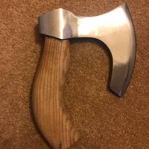 May include: A hand-crafted axe with a wooden handle and a curved, silver blade. The axe is made of high-quality materials and is perfect for a variety of tasks.