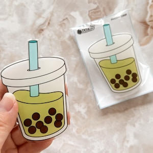 May include: A clear plastic sticker of a boba tea cup with a green drink and brown boba pearls. The sticker has a blue and white straw.