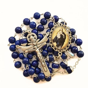 May include: A blue lapis lazuli rosary with a silver crucifix and a silver pendant featuring a religious image.