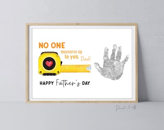 May include: Framed print with a Father's Day theme. The design features a yellow tape measure with a heart, a handprint, and the text "NO ONE measures up to you, Dad!" and "HAPPY Father's DAY". The frame is light brown.