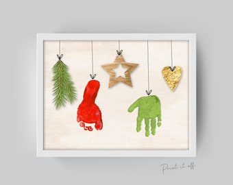 May include: A white framed print with a beige background featuring a red footprint, a green handprint, a gold heart, a brown star, and a green pine branch, all hanging from strings. The text "Print it off" is at the bottom of the print.