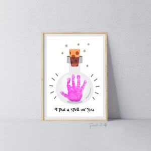 May include: A printable art print featuring a pink handprint inside a clear glass bottle with a cork stopper. The bottle is surrounded by gold stars and the text "I put a spell on you" is below the bottle.
