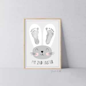 May include: A gray bunny rabbit with pink cheeks and white ears. The bunny's ears are made from baby footprints. The text "MY 2ND EASTER" is printed below the bunny.
