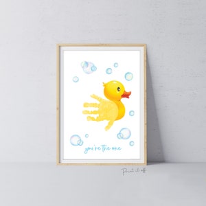 Peut inclure: Un canard en caoutchouc jaune avec une empreinte de main sur son corps, entouré de bulles bleues. Le texte "you're the one" est écrit sous le canard.