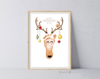 May include: A printable Christmas craft for kids. A reindeer made with a footprint, brown antlers, and red and gold ornaments. The text reads "Cutest Reindeer of All".