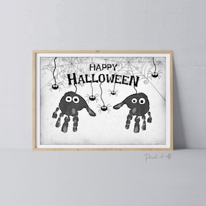 Pode incluir: Arte de Halloween imprimível em preto e branco com aranhas de impressões de mãos penduradas em teias de aranha com o texto "Happy Halloween".